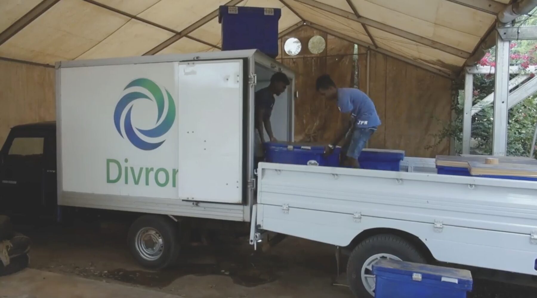 Two men loading blue insulated crates into a Divron box truck